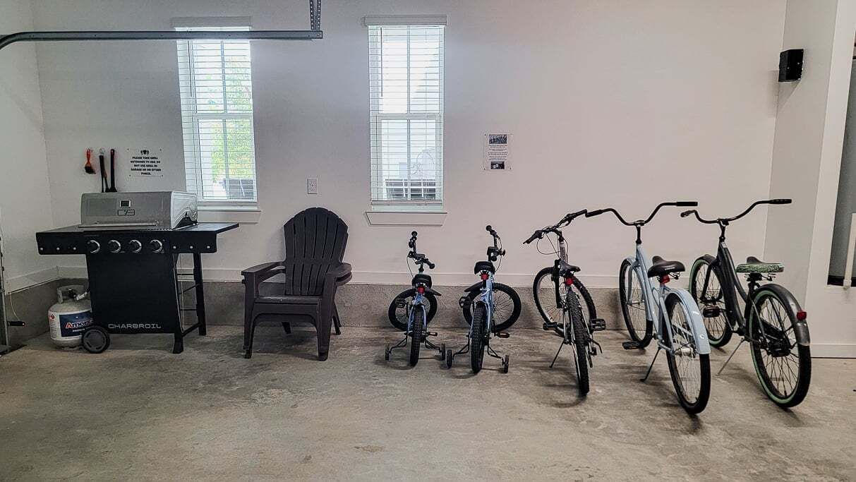 A room with a kitchenette, a chair, and several bicycles.