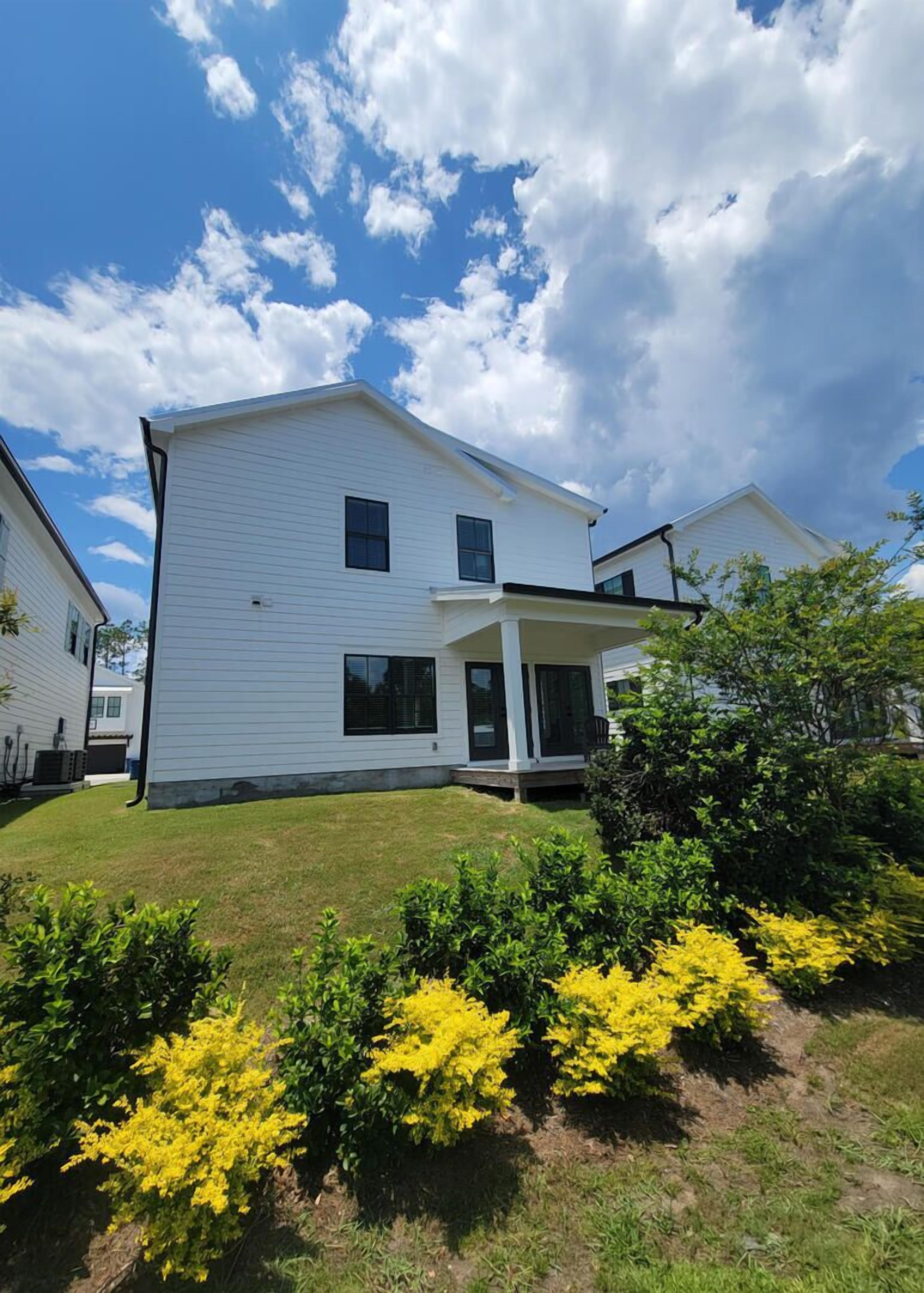 A two-story residential building with a covered porch and a well-maintained lawn.