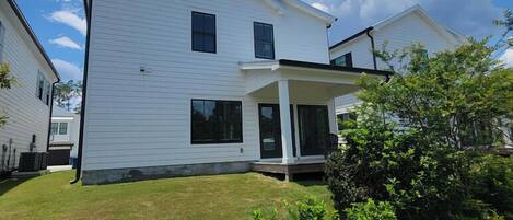 A two-story residential building with a covered porch and a well-maintained lawn.