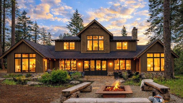 A large, two-story log cabin with a fire pit in the front yard, surrounded by trees. - Alpine Star | Stay on the Green @ Family Friendly Rates (Cle Elum)