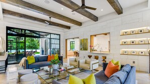 A spacious living room with a modern design, featuring a large sofa, a coffee table, and a dining area. - Above Lakeside I Lakefront | Pickleball I Pool/Spa l Firepit I Luxe Services (Austin)