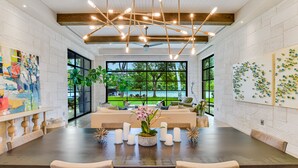 A spacious dining area with a long table, multiple chairs, and a ceiling light fixture. - Above Lakeside I Lakefront | Pickleball I Pool/Spa l Firepit I Luxe Services (Austin)