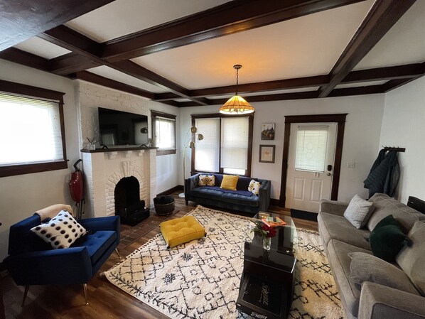 A living room with a fireplace, a sofa, a coffee table, and a television mounted on the wall. - East Nashville Cozy and Convenient - Chill Spring Specials! (Nashville)