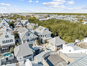 A residential area with multiple houses, a swimming pool, and a large green area in the background. - Rosemary Home with Private Pool and Bikes (Rosemary Beach)