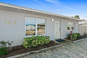 A single-story building with the number 103 on the wall, a door labeled 'B', and a small garden area with plants. - Paradise Palms - Nautilus Suite - Heated Pool! (St. Augustine)