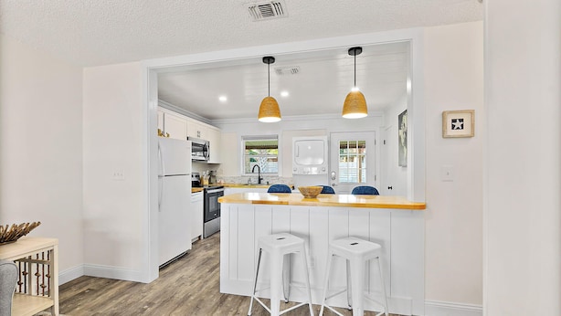 A modern kitchen with white cabinetry, a wooden countertop, and two bar stools. - Paradise Palms - Nautilus Suite - Heated Pool! (St. Augustine)
