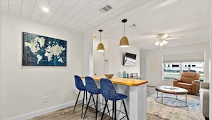 A modern kitchen with a bar area, a world map artwork, and a ceiling fan. - Paradise Palms - Nautilus Suite - Heated Pool! (St. Augustine)