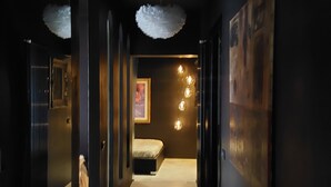 A hallway with a bed, a painting, and a light fixture. - Luxury Design Apartment | Total Sea View & Private Jacuzzi (La spezia)