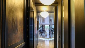 A hallway with a polished floor, a large chandelier, and a piano in the background. - Luxury Design Apartment | Total Sea View & Private Jacuzzi (La spezia)