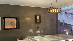 A modern bathroom with a large bathtub, a decorative wall with framed artwork, and a hanging light fixture. - Luxury Design Apartment | Total Sea View & Private Jacuzzi (La spezia)