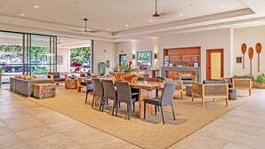 A spacious lobby with a reception desk, seating area, and large windows offering a view of the street. - Hawaii Life Rentals - Kahana Ocean Front (Lahaina)