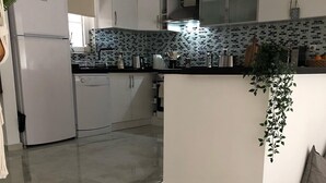 A modern kitchen with white cabinets, a black countertop, and a tiled backsplash. - Villa Ayshella , Luxury Ovacik Villa with stunning mountain views and sunsets (Ovacık)