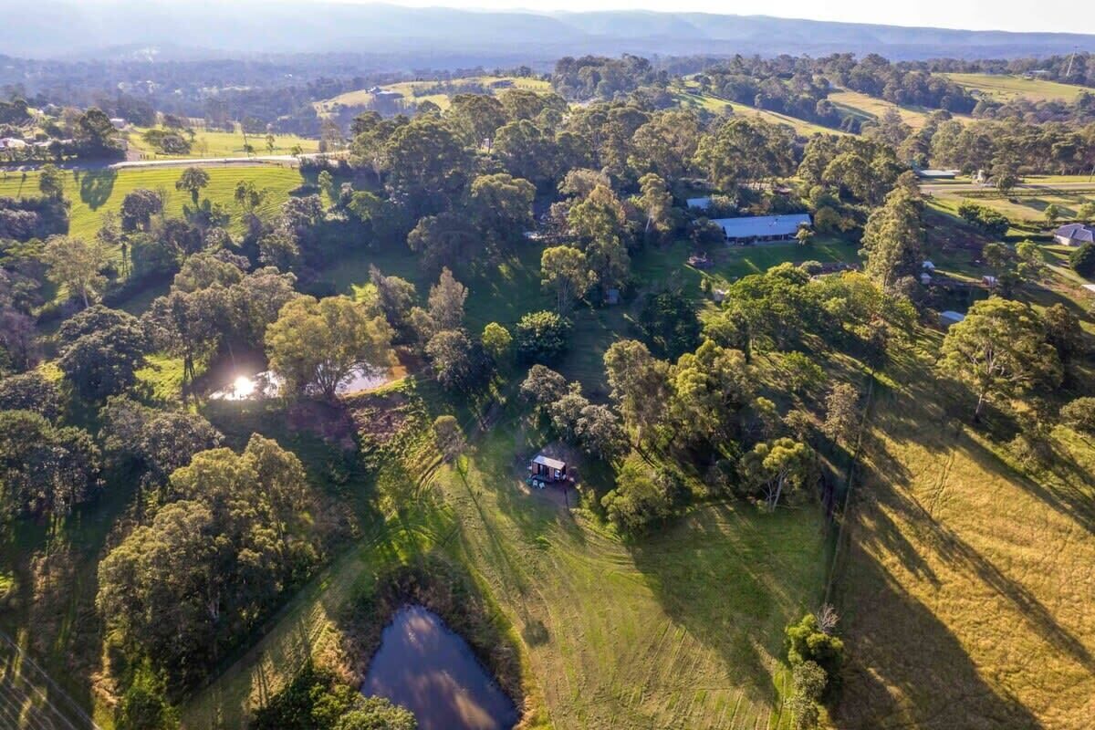 An aerial view of a rural landscape with a small house surrounded by trees and fields.