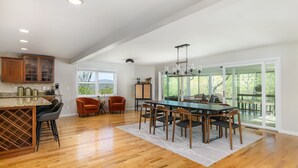 A spacious kitchen with a large island, wooden flooring, and a dining area with a long table and chairs. - Grey Eagle Lodge | Pet Friendly, Deck & Game Room 10 Min. from Black Mtn (Black Mountain)