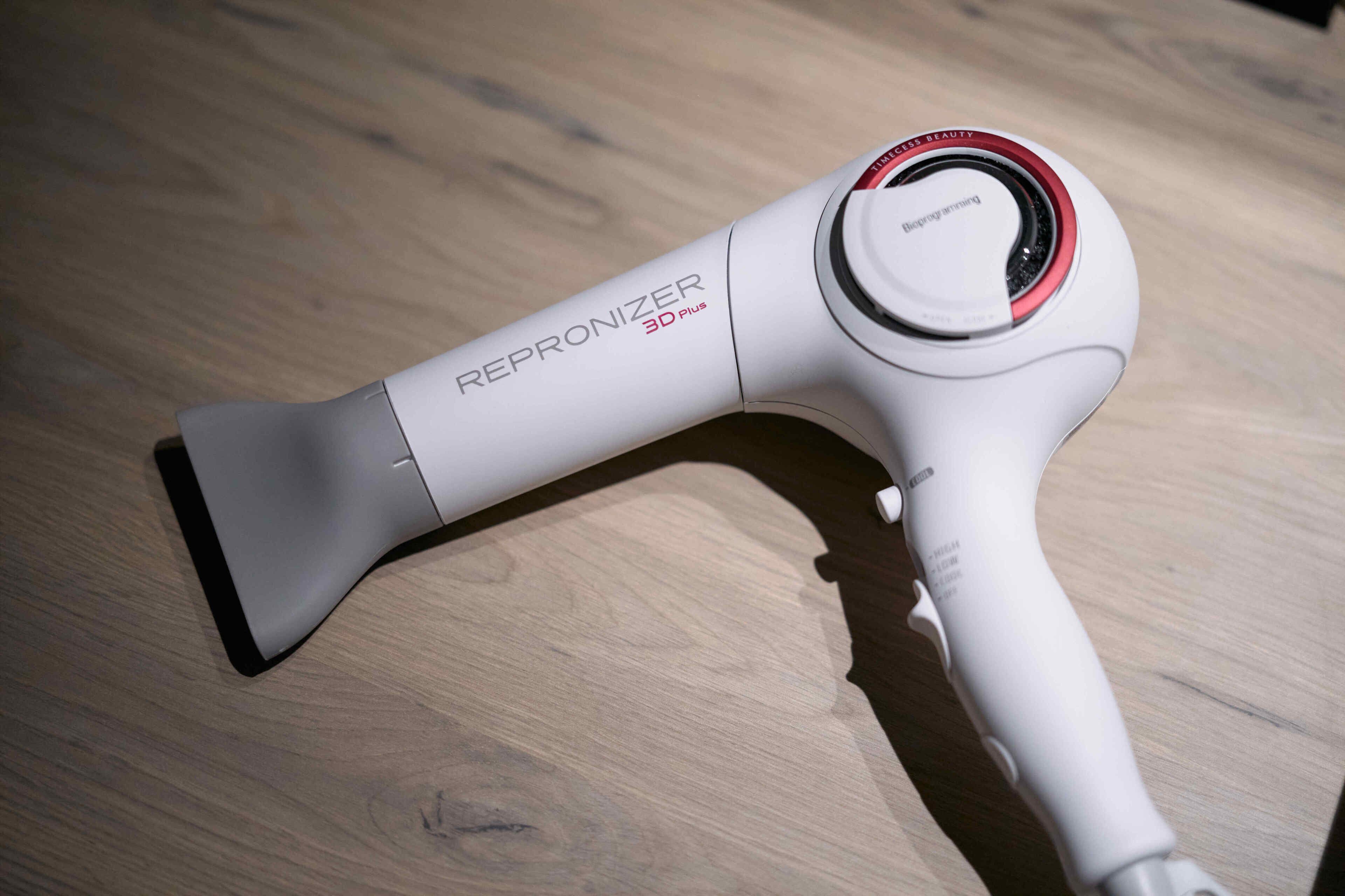 A white hairdryer with the brand name "REPRONIZER 3D PLUS" on a wooden surface.