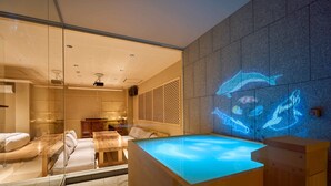 A modern spa room with a glass-enclosed seating area, a wooden reception desk, and a wall-mounted projection of a dolphin. - KONJAKUSO Osaka Tempozan "IKESU" Projection Mapping SPA "TAKADORO" Wheel View (Osaka)