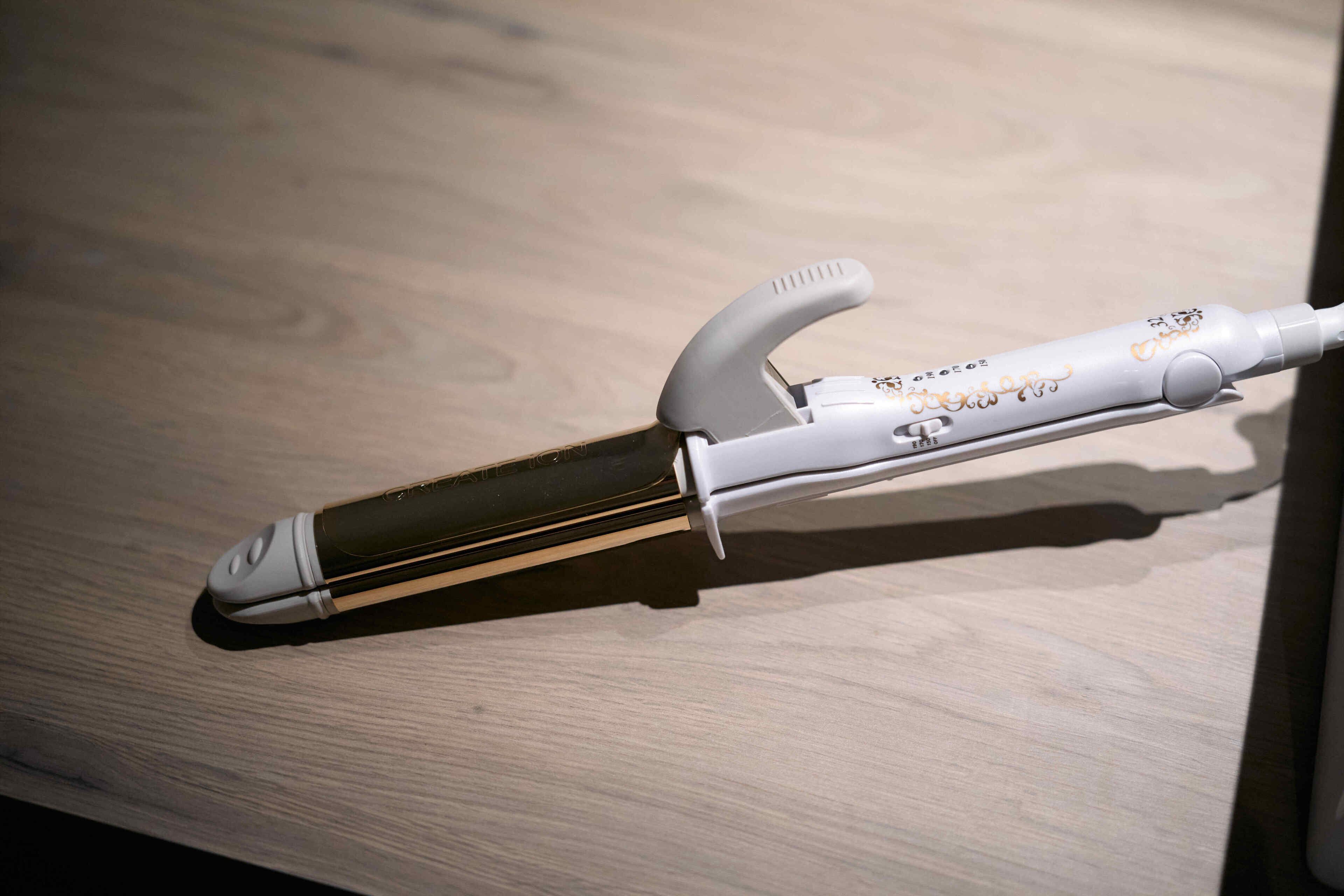 A curling iron on a wooden surface.
