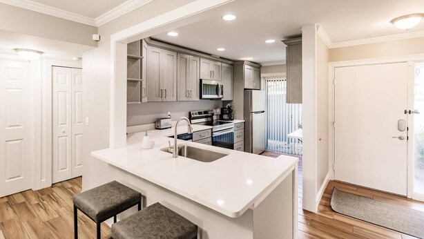 A modern kitchen with white cabinetry, a central island with a sink, and a microwave above the stove.