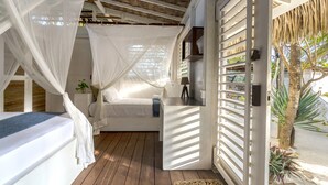 A bedroom with a canopy bed, wooden flooring, and a view of the outdoors.