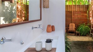 A bathroom with a large mirror, a bathtub, a sink, and two ceramic cups on the countertop.
