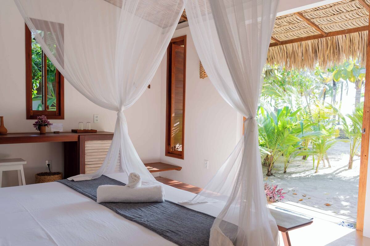 A bedroom with a bed, a desk, and a window.