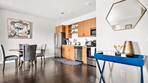 A modern kitchen with wooden cabinets, stainless steel appliances, and a blue console table. - TC Condo | Steps to Tart Trail | Near Downtown (Traverse City)