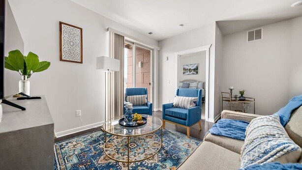 A modern living room with a sofa, armchairs, a coffee table, and a patterned rug. - TC Condo | Steps to Tart Trail | Near Downtown (Traverse City)