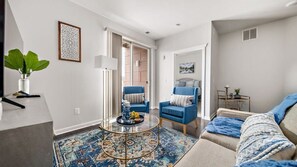 A modern living room with a sofa, armchairs, a coffee table, and a patterned rug. - TC Condo | Steps to Tart Trail | Near Downtown (Traverse City)
