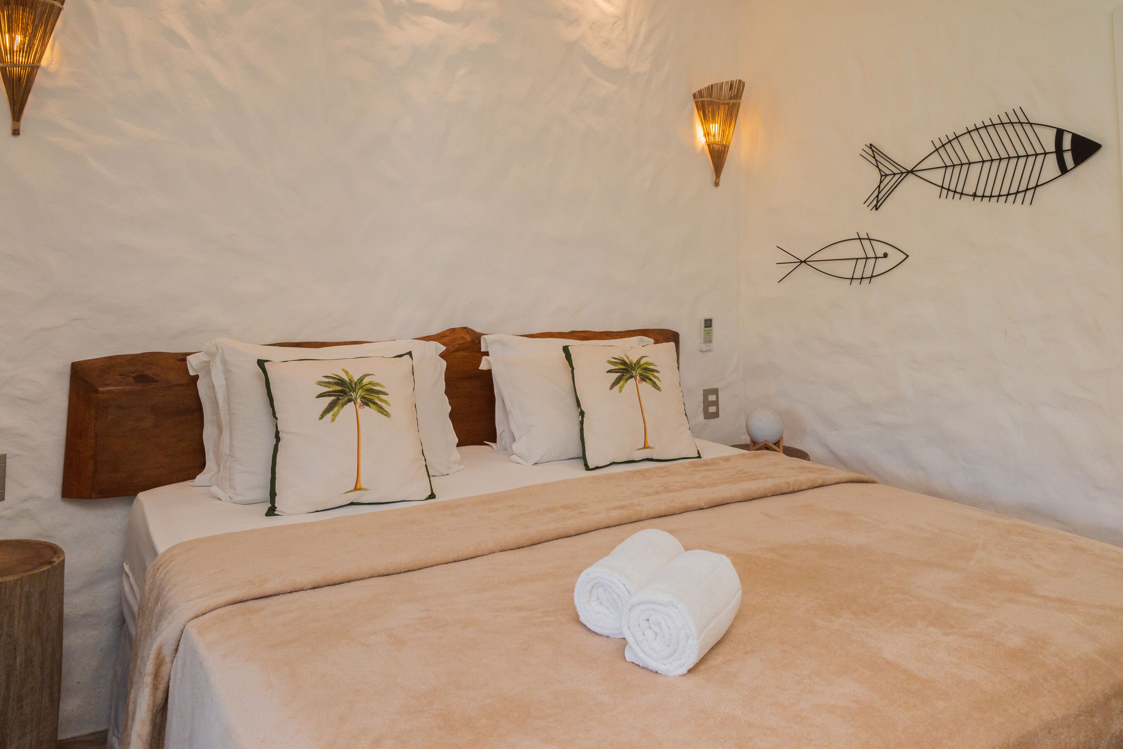 A bedroom with a bed, pillows, a blanket, and wall art.