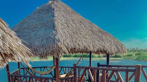 Un muelle de madera con techos de paja que se extiende sobre aguas azul cristalino.