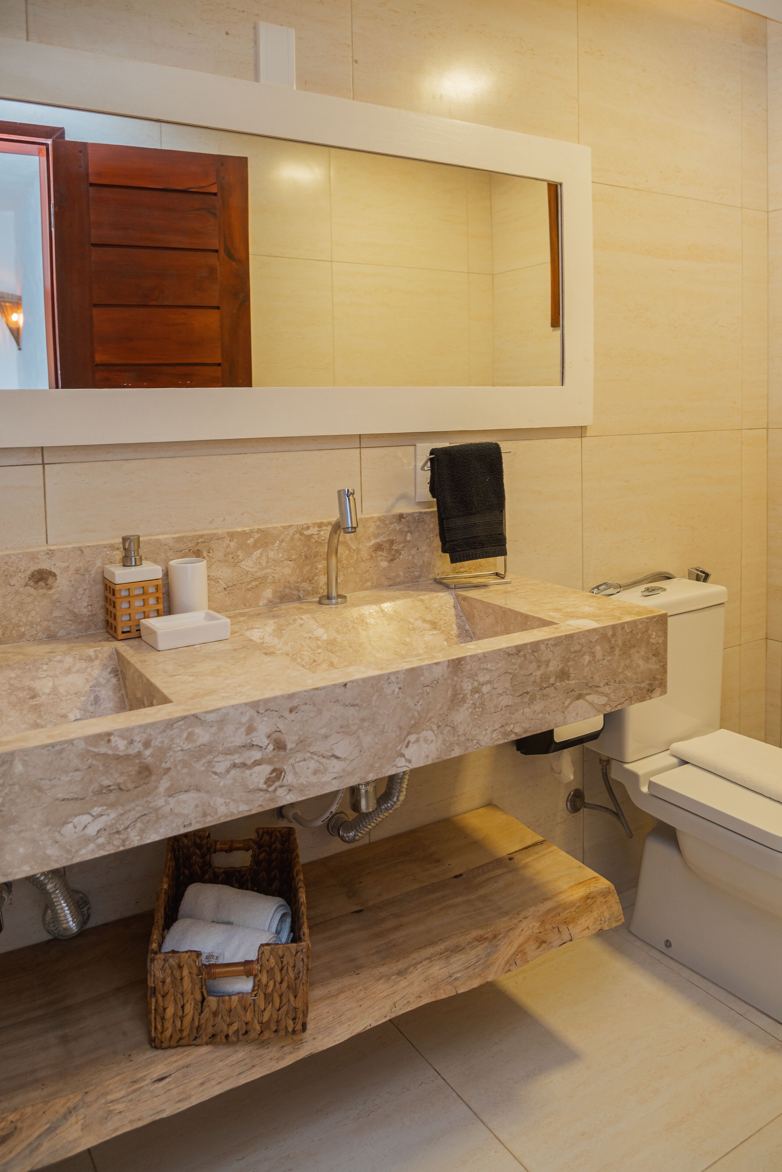 Une salle de bain avec un lavabo en marbre, un meuble-lavabo en bois, un miroir, un porte-serviettes et des toilettes.