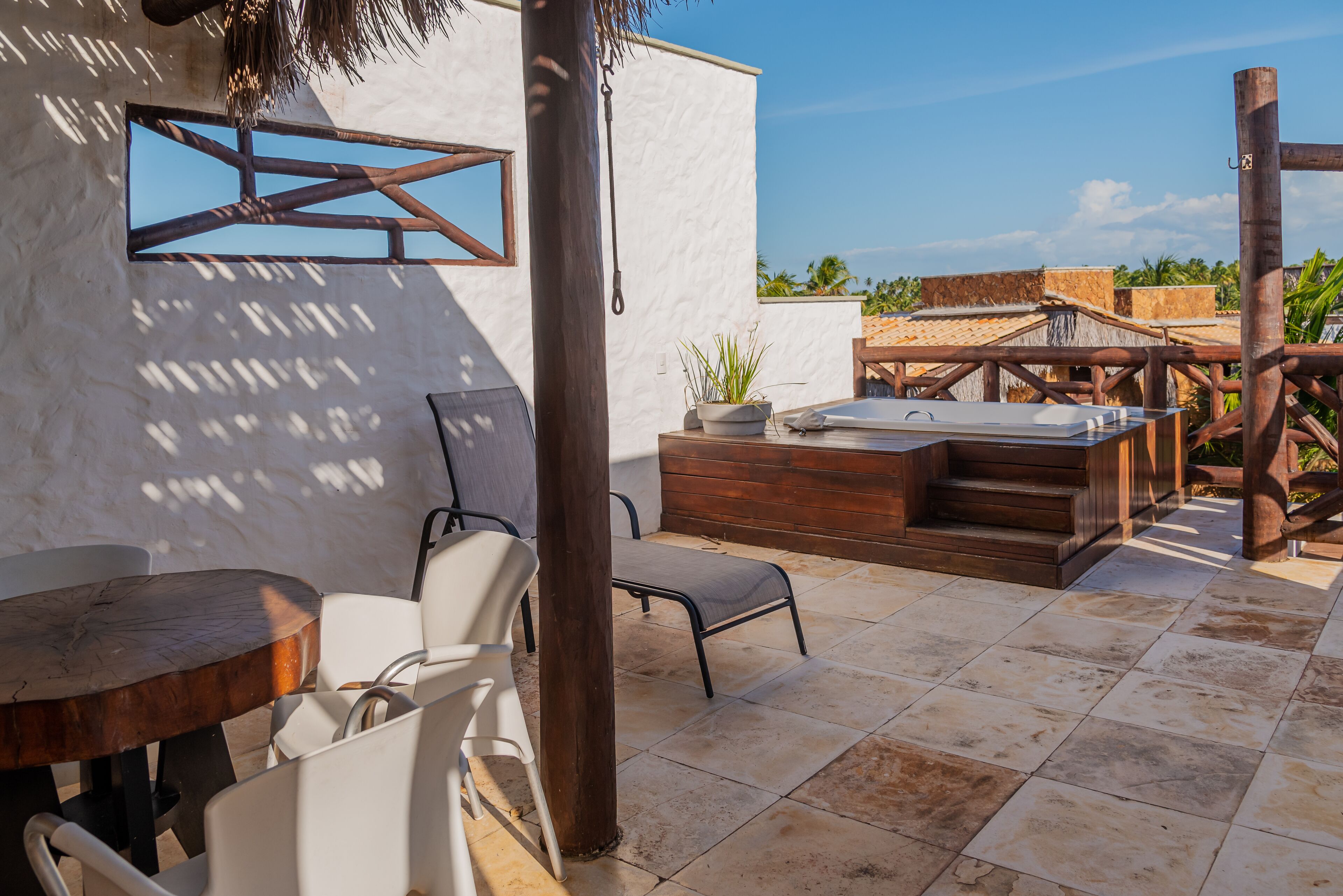 Un patio con una mesa y sillas de madera, un jacuzzi y vistas de los edificios circundantes.