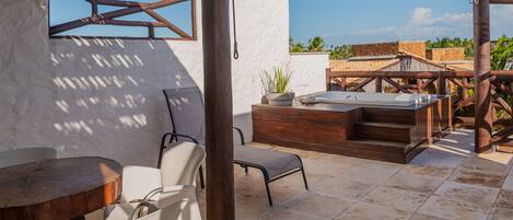 Un patio con una mesa y sillas de madera, un jacuzzi y vistas de los edificios circundantes.