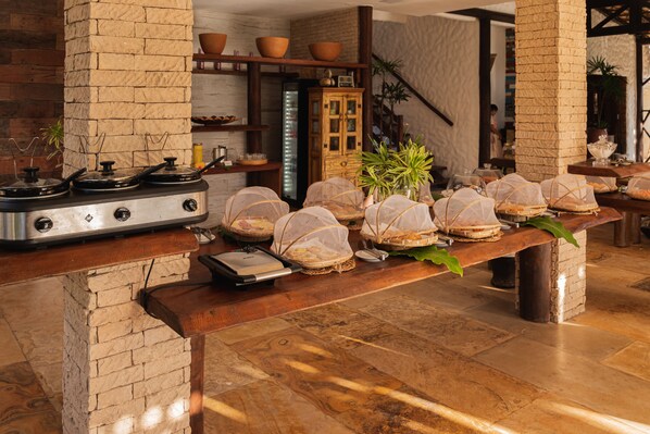 Una cocina con un pilastra de ladrillo, una estufa y una mesa de madera con alimentos cubiertos.