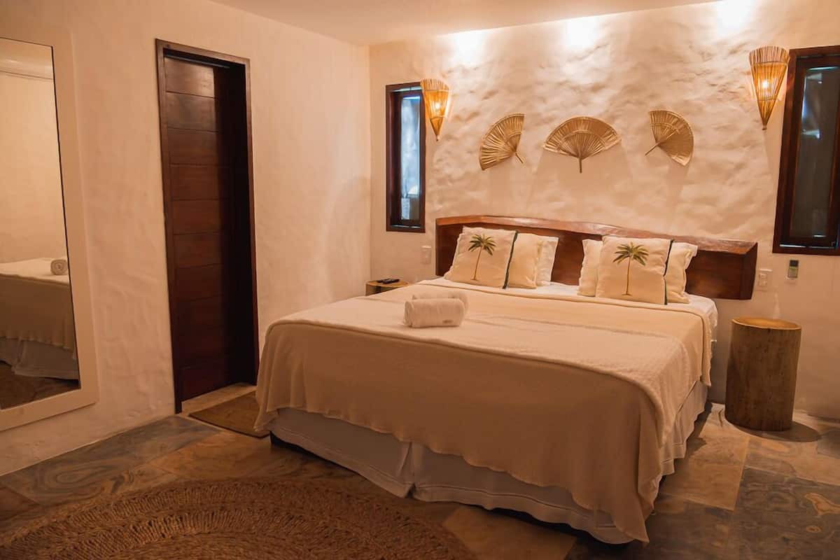 Ein Schlafzimmer mit einem großen Bett, einer Holztür und einer Wand mit strukturierter Oberfläche und Wandleuchten.