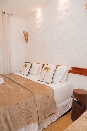 A hotel room with a bed, a wooden headboard, a bedside table, and a wall-mounted light fixture. - Moriá Eco Lodge (Amontada)