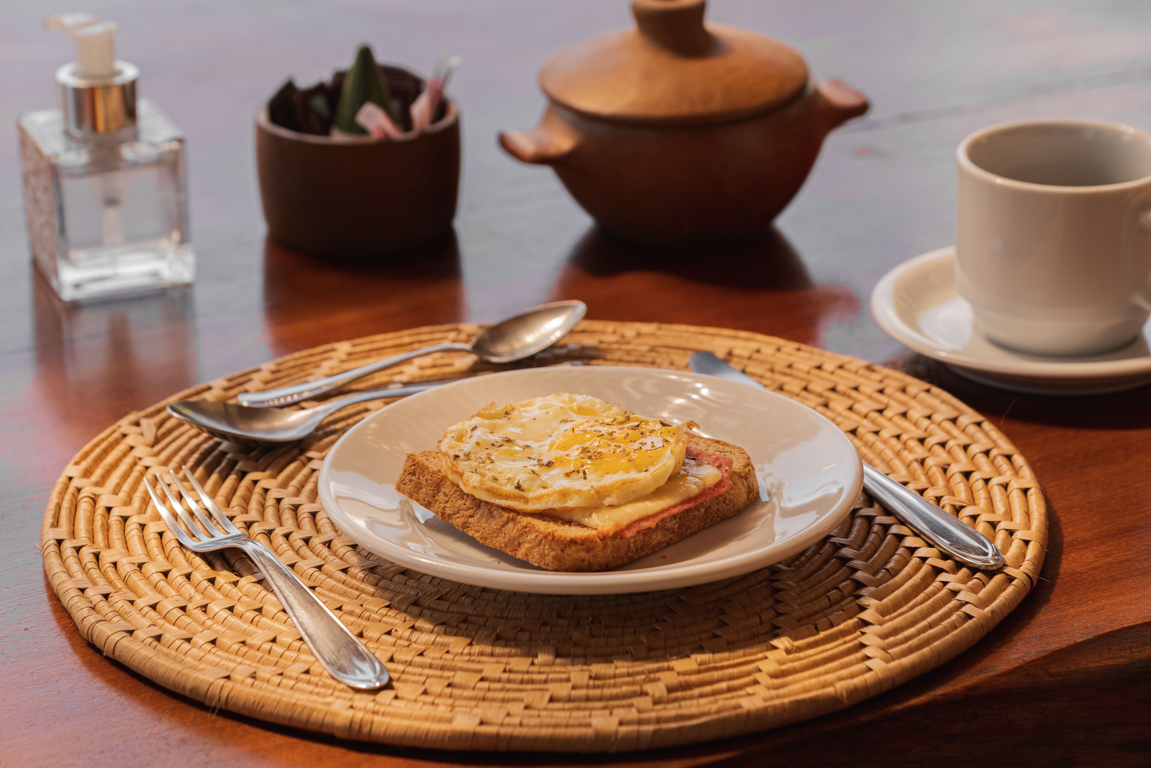 A breakfast setting with toast, eggs, and a cup on a woven placemat.