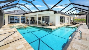 Ein überdachter Pool mit Glasdach, umgeben von Sitzmöglichkeiten im Freien und einer Terrassenfläche.