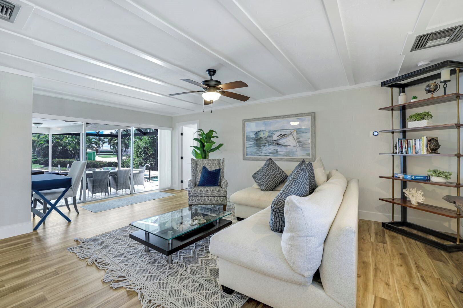 A spacious living room with a glass coffee table, a sofa, and a bookshelf.
