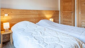 A double bed with white bedding in a room with wooden paneling on the walls and a wooden door. - Altaka 5 - Beautiful 2 bedrooms apartment (MORZINE)