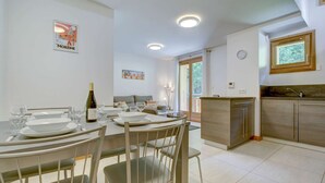 A dining area with a table set for four, a bottle of wine, and a painting on the wall. - Altaka 5 - Beautiful 2 bedrooms apartment (MORZINE)