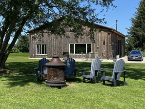 Un bâtiment rustique en bois doté d’un patio, d’un espace extérieur aménagé avec des sièges et d’un foyer.