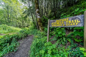 Explore the Nature Fitness Trail, sponsored by Scar, at the entrance to a serene forest with a dirt path leading into the woods.