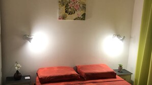 A room with a bed, two bedside tables, a wall-mounted light, and a small potted plant. - Villa de Charme à Bois Court (10 people) (Le Tampon)