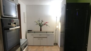 A compact kitchen with a Bosch oven, a Daewoo refrigerator, and a small cabinet with a vase of flowers. - Villa de Charme à Bois Court (10 people) (Le Tampon)