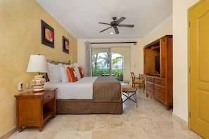 A hotel room with a bed, a nightstand, a TV cabinet, and a balcony with a view of palm trees.