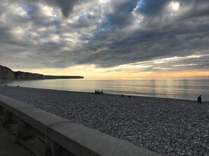A pebbled beach with a stone railing, calm sea, and overcast sky. - Charming little fisherman's cottage, in the center of Fécamp, 5 minutes from the harbor (Fécamp)