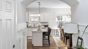 Una cocina moderna con armarios blancos, una isla central y un comedor con sillas y una mesa.