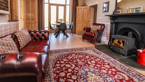 A living room with a leather sofa, a patterned rug, a fireplace, and a dining area with a table and chairs.