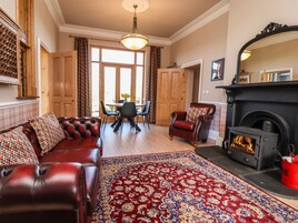 A living room with a leather sofa, a patterned rug, a fireplace, and a dining area with a table and chairs.